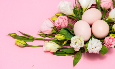 Easter background with Easter eggs and spring flowers. Top view with copy space. Nest with eggs decorated with beautiful flowers on a pink background.