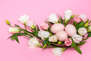 Obraz premium Easter background with Easter eggs and spring flowers. Top view with copy space. Nest with eggs decorated with beautiful flowers on a pink background.