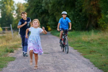 Portrait of three siblings children. Two kids brothers boys and little cute toddler sister girl walking together. Happy healthy family playing, walking, active leisure on nature