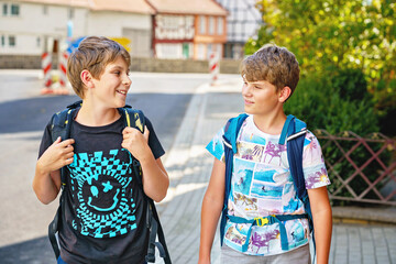 Two kid boys with backpack or satchel. Schoolkids on the way to school. Healthy smiling children,...