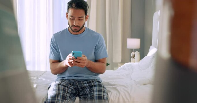 Phone, social media and wake up with a man on his bed in the bedroom of his home in the morning. Web, internet and communication with a young male in pyjamas reading and sending a text message