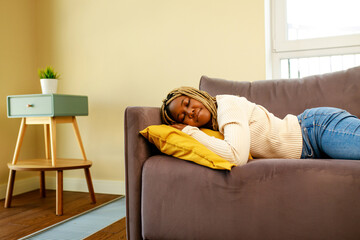 tired latin hispanic woman taking nap on the sofa during the day