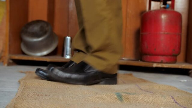 A closeup shot of a man wiping his shoes on a rucksack doormat - cleanliness and hygiene. A rural household in an Indian village - a poor family  a single man  BPL
