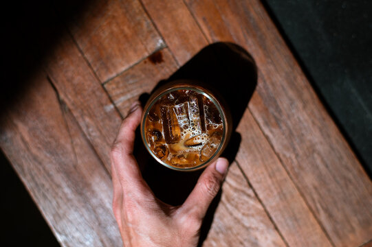 hand holding a take-out iced coffee on black table