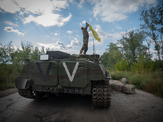 The war in ukraine, the offensive of the ukrainian army captured by the russian military, russian military equipment on which the soldier sets the ukrainian flag. High quality photo