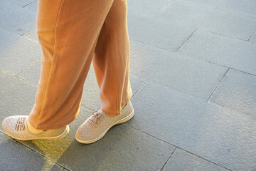 Standing on a tiled floor with a copy space composition. a female leg model who wears long pants...