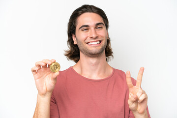 Young handsome man holding a Bitcoin isolated on white background smiling and showing victory sign