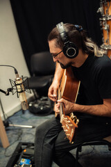 man plays the guitar. guitar sound recording. headphones and microphone
