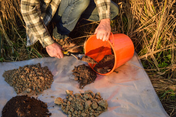 Male agronomy specialist preparing for soil analysis at field. Man farmer arranging soil samples,...