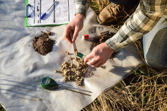Closeup of agronomy specialist preparing soil samples for laboratory analysis outdoors. Professional farmer filling sample bag with material sampling at field. Environment research, soil certification