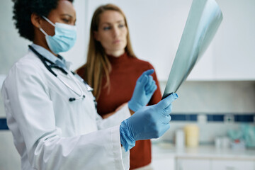 Close up of doctor examining X-ray image with her patient at medical clinic.