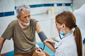 Senior man having his blood pressure measured during medical examination at doctor's office. © Drazen