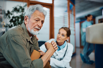 Worried senior man with female doctor in waiting room at clinic.