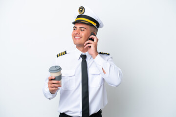 Airplane pilot caucasian man isolated on white background holding coffee to take away and a mobile
