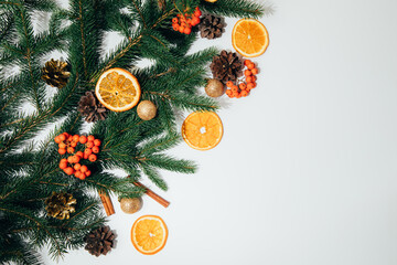 Fototapeta na wymiar New Year, Christmas background. New Year's decor on a white background with branches of a green Christmas tree, pine cones and slices of dry orange. Flat lay
