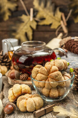 Autumn tea concept. Cookies with pumpkin puree, black tea in a glass teapot, fall decor