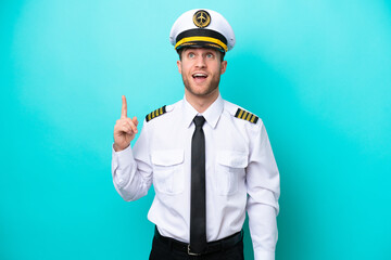 Airplane caucasian pilot isolated on blue background pointing up and surprised