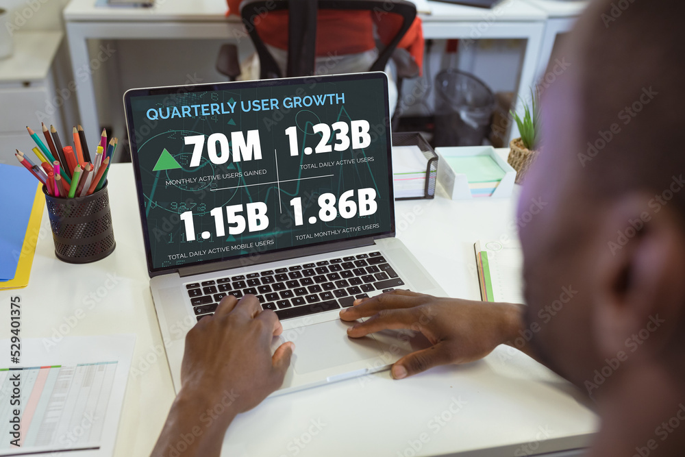 Poster Over shoulder view of african american businessman using laptop with user growth figures on screen