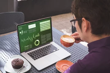 Keuken foto achterwand Aziatische plekken Over schouder zicht op Aziatische zakenman die koffie drinkt, met grafieken en diagrammen op laptopscherm