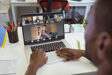 Over shoulder view of african american businessman making laptop video call with diverse colleagues