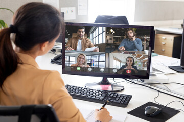 Over shoulder view of asian businesswoman making video call with diverse colleagues on screen