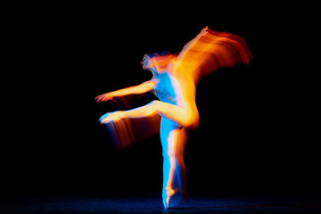 Young and graceful female ballet dancer dancing over dark background in mixed neon light. Art, motion, action, flexibility, inspiration concept.