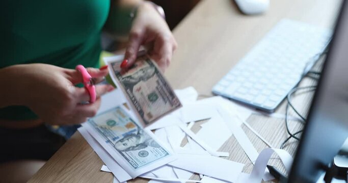 Woman cuts out counterfeit dollars, close-up