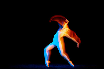 Fototapeta na wymiar Ease of movement. Tender female ballet dancer dancing solo dance over dark background in mixed neon light. Art, flexibility, inspiration and beauty concept.