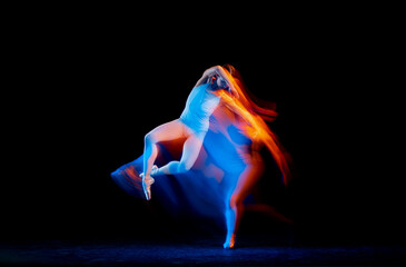 Obraz na płótnie Canvas Dynamic portrait of tender slim girl, female ballet dancer in art performance isolated over black background in mixed bright neon light.