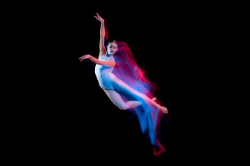 Ease of movement. Tender female ballet dancer dancing solo dance over dark background in mixed neon light. Art, flexibility, inspiration and beauty concept.