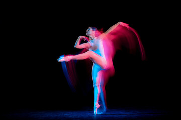 Flexible and beautiful girl, ballet dancer in motion over dark background in mixed neon light. Grace, art, flexibility, inspiration concept.