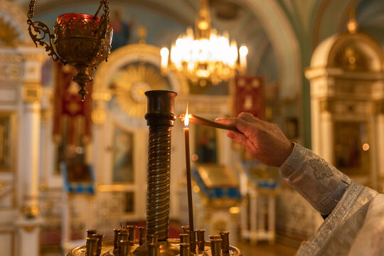 Orthodox Church. Christianity. Hand of priest lighting burning candles in traditional Orthodox Church on Easter Eve or Christmas. Religion faith pray symbol.