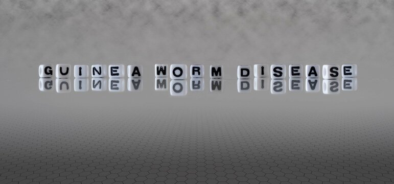 guinea worm disease word or concept represented by black and white letter cubes on a grey horizon background stretching to infinity