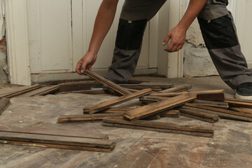 Home improvement. Construction worker or handyman is removing old wooden parquet flooring using...