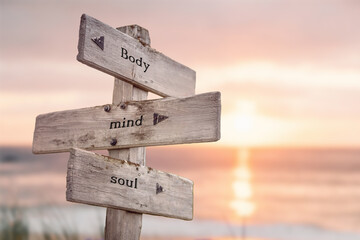 body mind soul text quote engraved on wooden signpost outdoors on the beach with sunset theme. - obrazy, fototapety, plakaty