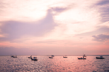 Beautiful sunrise on sea background with tropical wooden fishing boat pink tone