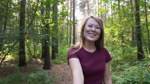 Couple in love, having an aventure in a forest POV. Girl leading, holding boyfriend hand, walking and smiling in a green park. Relationship point of view shot.