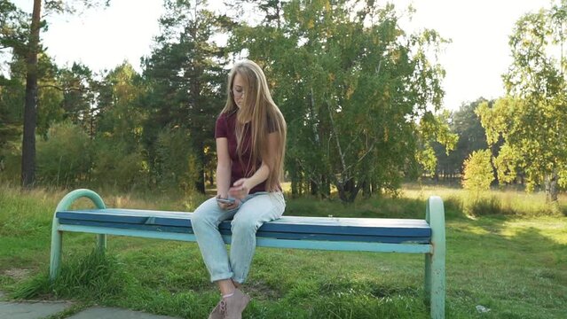 Sad and bored woman sitting on bench feels lonely and unhappy. Girl waiting or missing someone for a date. Unpleasant thoughts, suffering due brake up, bad romance and personal life troubles. 