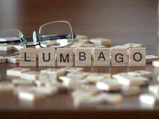 lumbago word or concept represented by wooden letter tiles on a wooden table with glasses and a book - obrazy, fototapety, plakaty