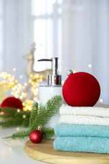 Stack of blue and white towels folded on the table, fir branches, Christmas balls and Christmas lights. SPA massage or beauty salon, relaxation and wellness in Christmas or New Year variant.