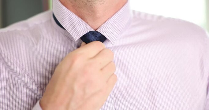 Closeup of man getting ready tying a necktie in morning