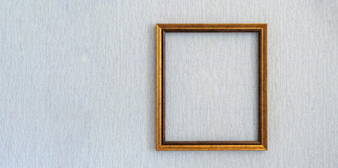 Baguette frame for picture or photograph of gold color hangs on  light wall.