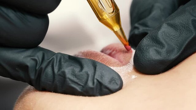 microblading lip tattoo 4k in a permanent makeup clinic, applying coloring pigment to lips with a tattoo machine, make-up pigmentation on a female face