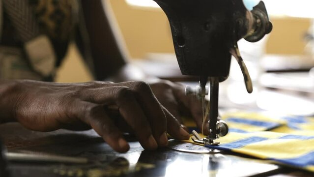 Woman in Sierra Leone sewing cloth together.