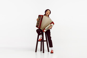 Portrait of talented beautiful woman playing accordion isolated over white studio background. Emotions