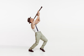 Portrait of young man playing clarinet isolated over white studio background. Stylish model
