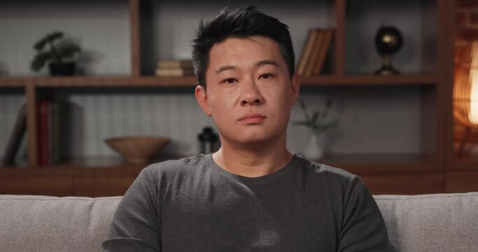 Portrait of Asian man looking at the camera at home, participating in a video conference