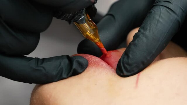 microblading lip tattoo 4k in a permanent makeup clinic, applying coloring pigment to lips with a tattoo machine, make-up pigmentation on a female face