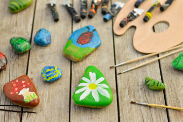 Fototapeta na wymiar Flat stones painted with acrylic paints. Do it yourself. Souvenirs that children can make.