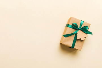 wrapped christmas or other holiday handmade present in paper with colored ribbon. Present box, decoration of gift on colourfull table, top view with copy space